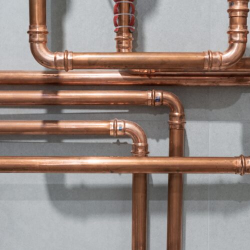 Complex network of polished copper pipes on wall
