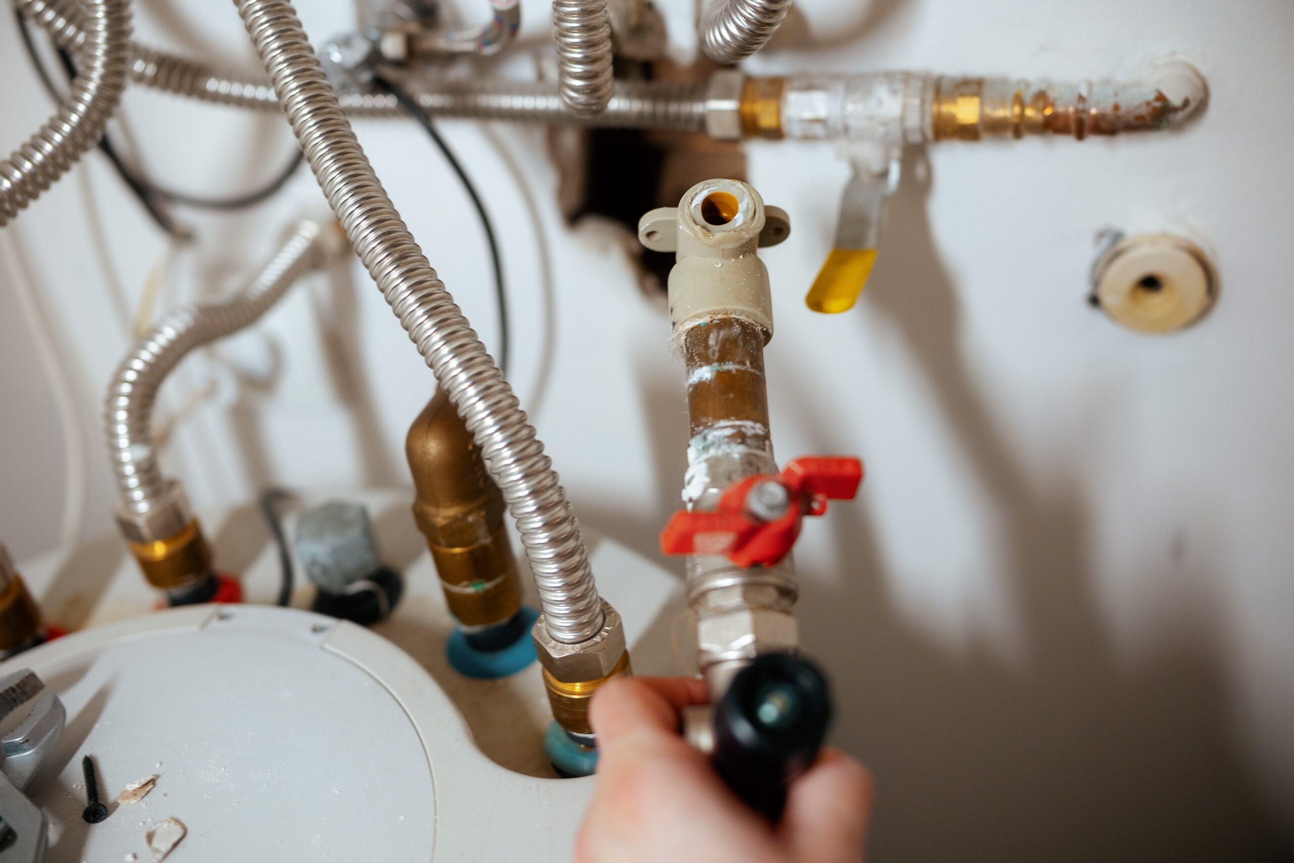 Person fixing water heater connections and pipes